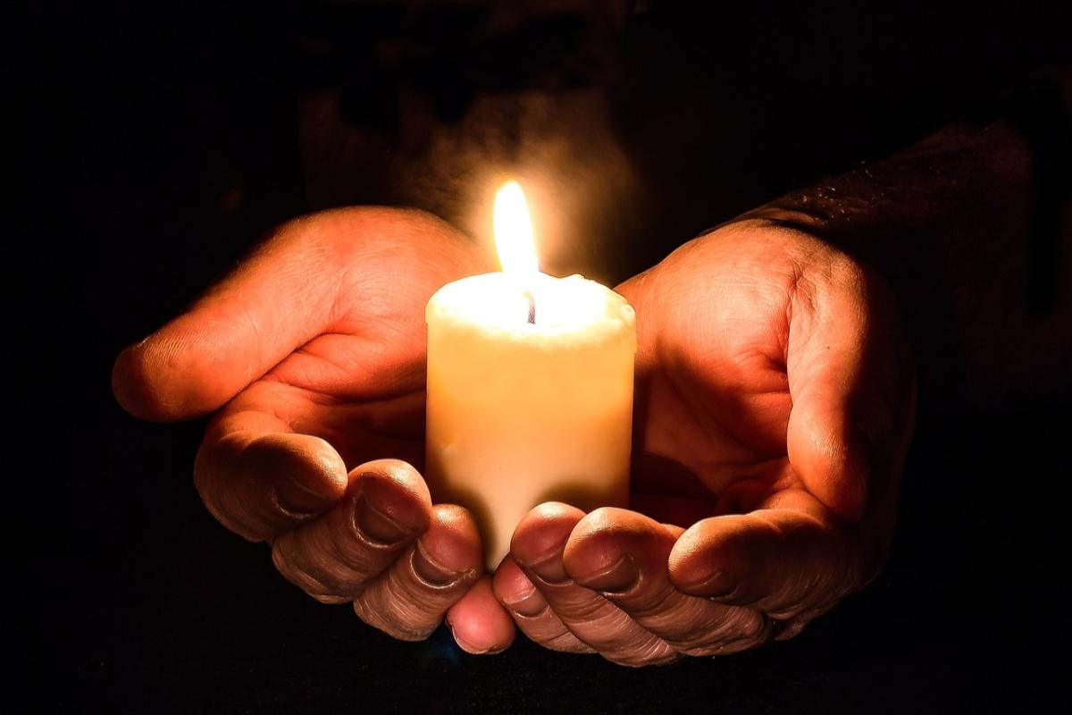 Candela accesa sorretta da due mani